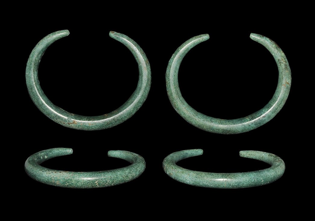 Bronze Age Bracelet Pair: 2nd millennium BC. A matched pair of bronze penannular bracelets, each a tapering rod with flattened ends. 128 grams total, 72mm (3"). From an old Munich collection; acquired on the German art market