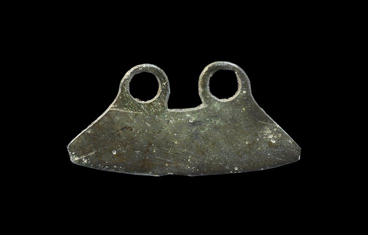 Bronze Age Double-Looped Razor: 2000-1000 BC. A small razor with trapezoidal blade and two rings to the upper edge, slightly curved cutting edge. 2.73 grams, 33mm (1 1/4"). Found near Ludford, Lincolnshire, UK; in 1982.