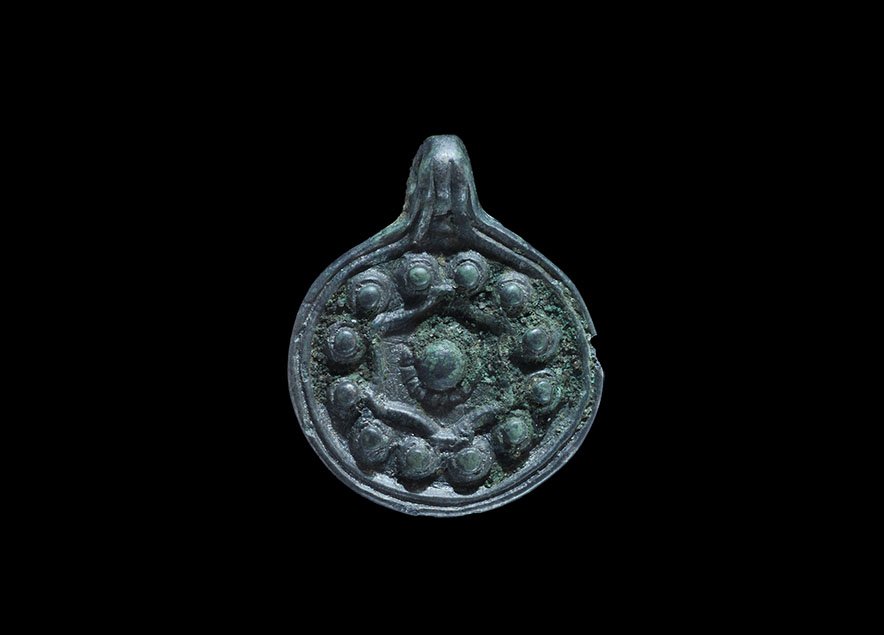 Viking Pendant with Cross and Bosses: 9th-12th century AD. A bronze discoid Scandinavian type pendant with raised rim and integral loop, cruciform motif in high relief with scrolls and bosses. 6.76 grams, 35mm (1 1/2"). From an old Munich