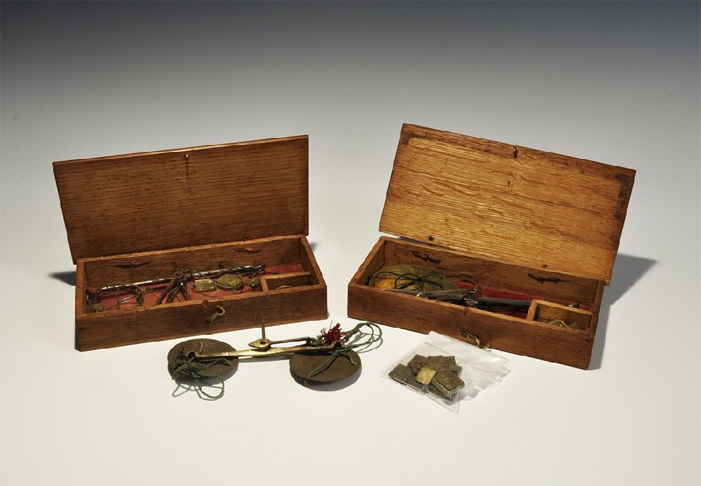 Post Medieval Cased Apothecary Scales & Weights Set: Late 19th-early 20th century AD. A mixed group comprising: a wooden cased set with white metal scale balance and two glass pans, full set of Avery 1847 round-type apothecary's weights in drams (2, 1 (