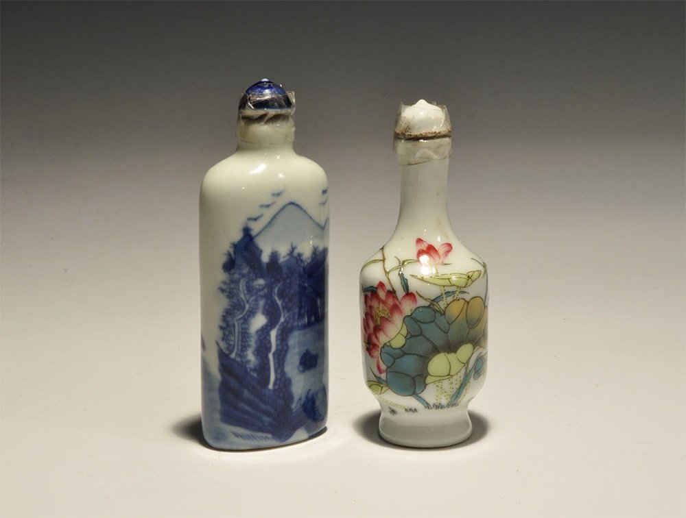 Chinese Style Perfume Bottle Group: 20th century AD. A pair of white-glazed ceramic perfume bottles comprising: one with deep shoulder, polychrome floral motif; one tall with blue landscape. 88 grams total, 85-90mm (3 1/2 - 3 3/4"). Acq
