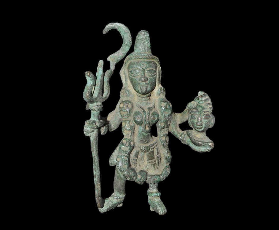 Indian Kali Goddess Statuette: 19th-early 20th century AD. A bronze figure of the Hindu goddess Kali shown with four arms; upper right holds scimitar, lower right a trident; upper left the severed head of a demon, lower left a bowl