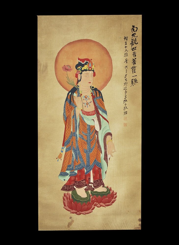 Chinese Kwan Yin Figure Scroll Painting: 20th century AD. A rectangular paper panel on a fabric backing with wooden roller; painting of a robed Kwan Yin standing on two lotus flowers with a nimbus to the head, holding a flower; two columns o