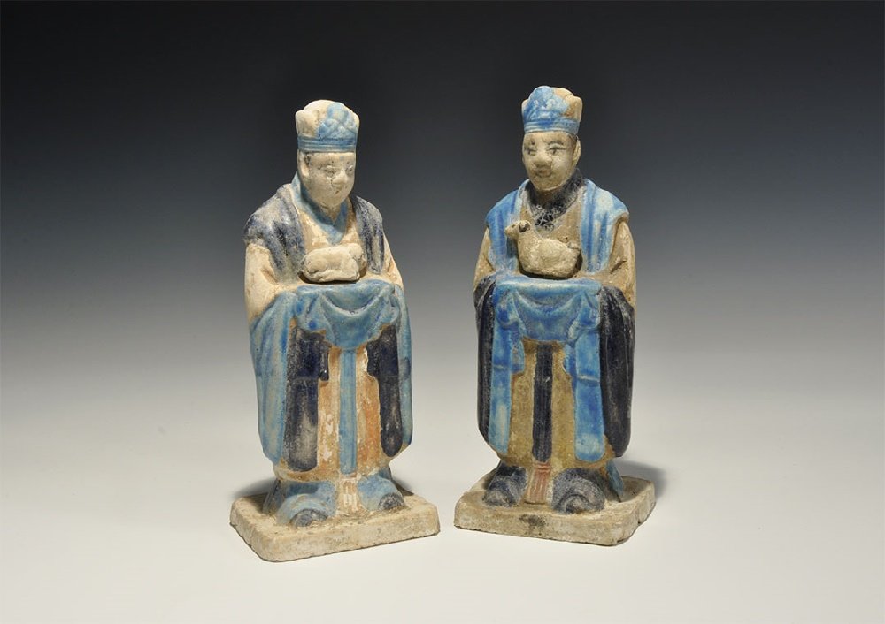 Chinese Blue-Glazed Zodiac Figurine Pair: An undated archaistic pair of glazed ceramic figurines in Ming Dynasty, 1368-1644 AD style comprising: one standing on a rectangular base in light blue robe with dark blue detailing holding a hen; the