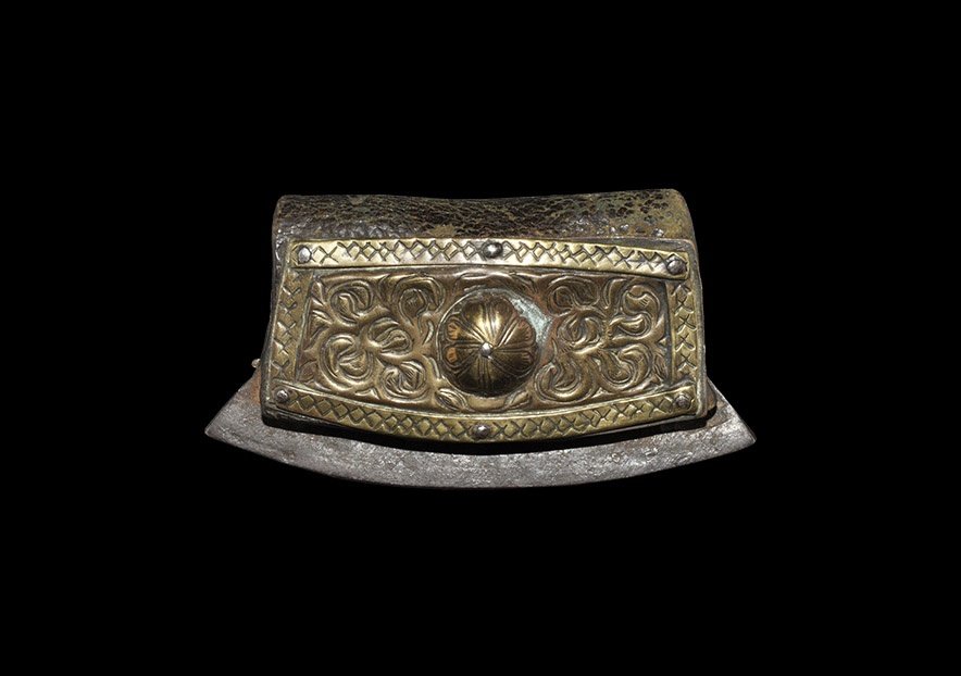 Post Medieval Iron Firesteel and Leather Tinder Pouch: 19th century AD. A pelta-shaped iron firesteel with folded leather tinder pouch to one face, two small holes in the hinge for suspension; rectangular brass plaque to the reverse with hatched border, s