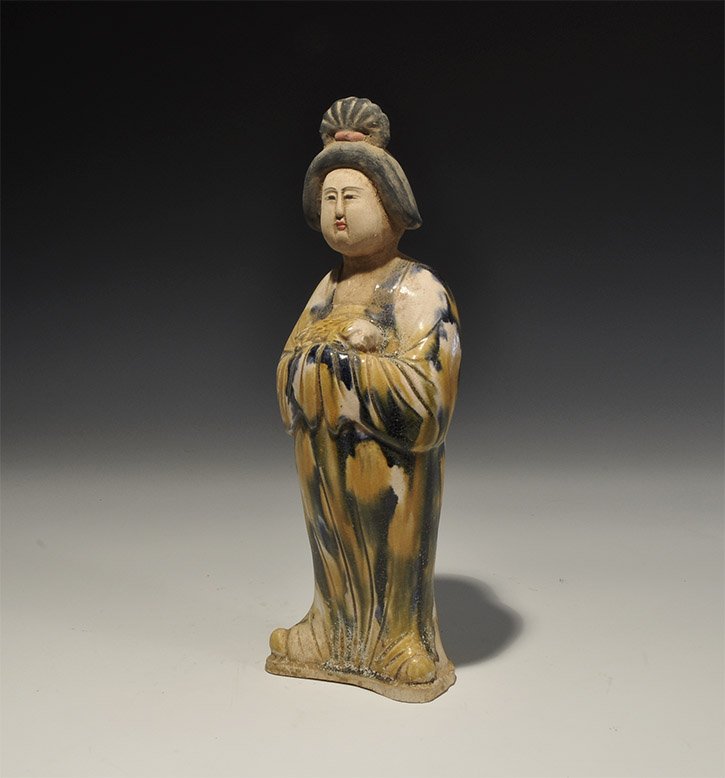 Chinese Noble Lady Figurine: . An undated archaistic part-glazed figurine of a robed lady with hands clasped in long sleeves cradling a miniature dog; hollow to the underside. 480 grams, 26cm (10"). Private collection, West Londo