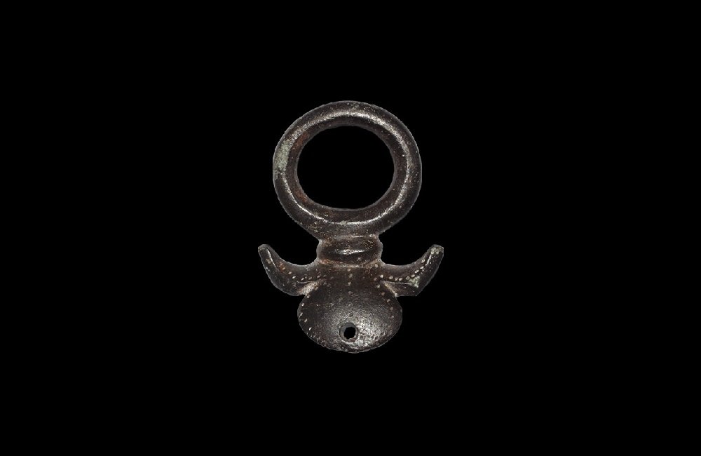 Romano- British Terret Ring: 1st century AD. A bronze terret with round-section loop, carinated collar above two lateral horns with pointille detailing, D-shaped pierced skirt. 29 grams, 45mm (1 3/4"). Ex Kelway collection; forme
