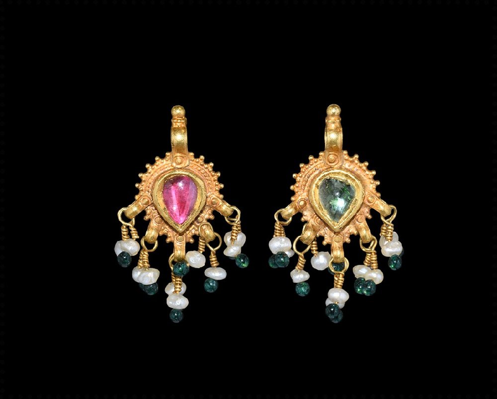 Byzantine Gold Spinel and Emerald Pendant: 10th century AD. A gold pendant formed as a piriform plaque with beaded detailing to both faces, granulation to the rim, integral loop with knop above; to one face an inset spinel cabochon and a simil