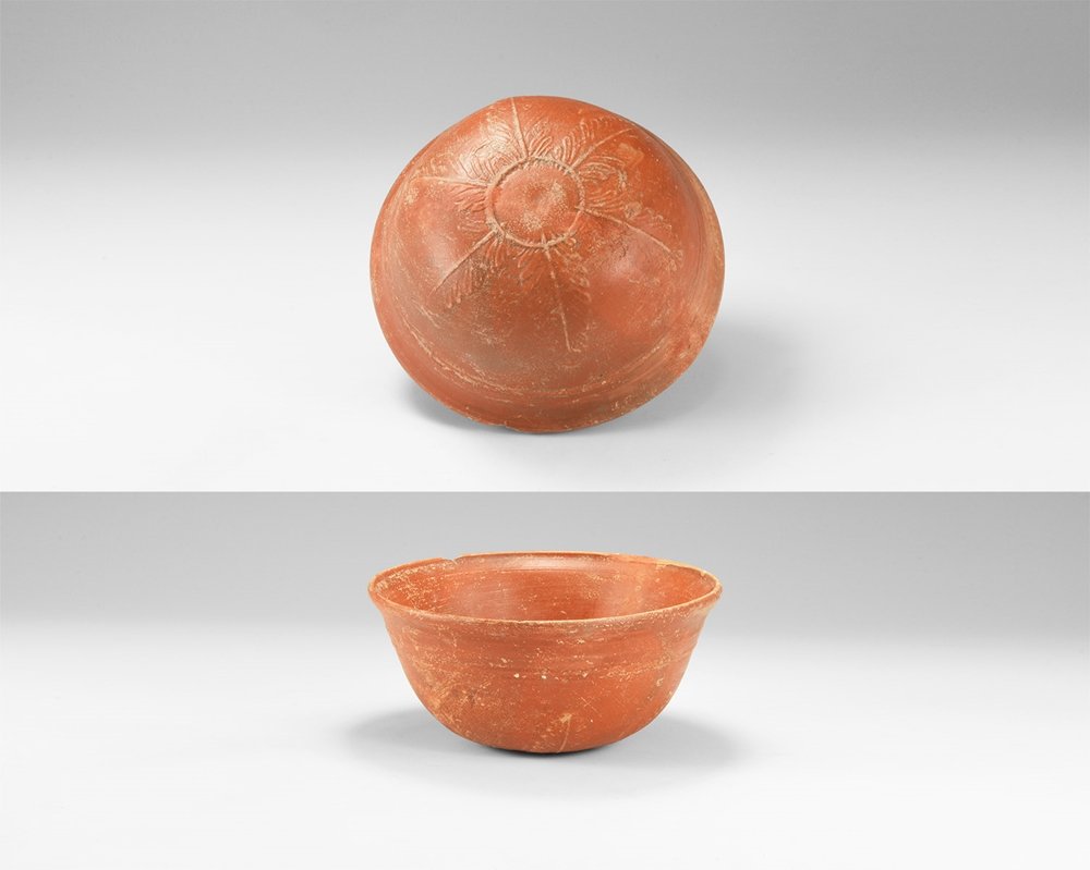 Roman Cup with Floral Decoration: 1st -3rd century AD. A ceramic terra sigillata cup with rounded underside and flared rim, low-relief palmettes extending from the basal ring up the sides. 124 grams, 12cm (4 3/4"). From a German colle