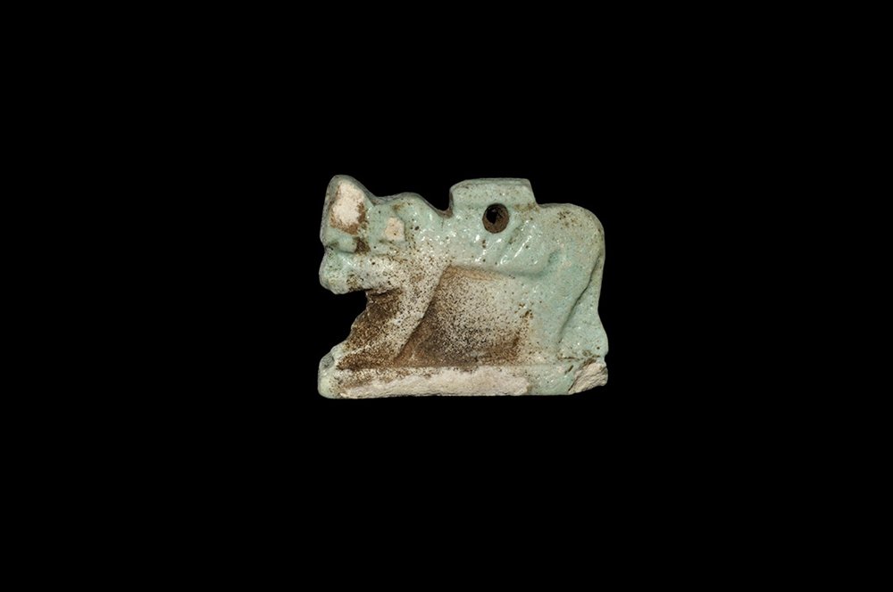 Egyptian Bull Amulet: Late Period, 664-332 BC. A large glazed composition bifacial amulet of a bull, either the sacred Apis or Mnevis bull, advancing on a rectangular base. Cf. Andrews, C. Amulets of Ancient Egypt, London,
