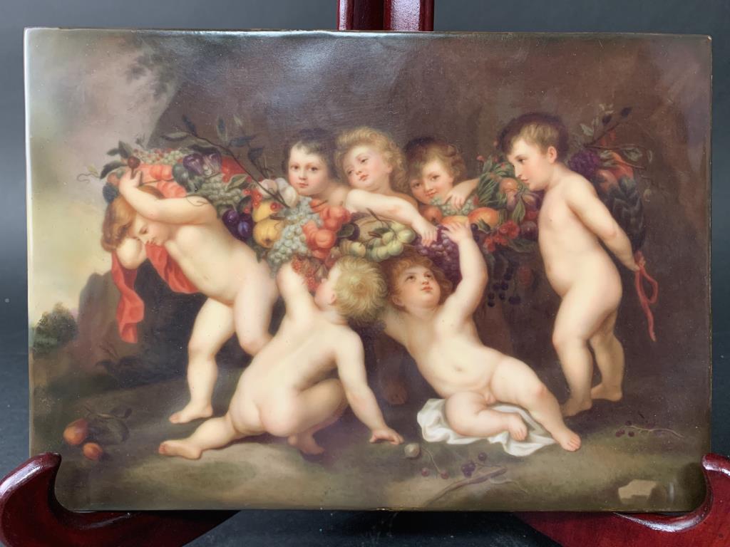 A BEAUTIFUL PORCELAIN PLAQUE, OF PUTTI: Holding a garland of flowers and fruits. Impressed with "KPM" at the back. L: 9.75in x H: 7in.