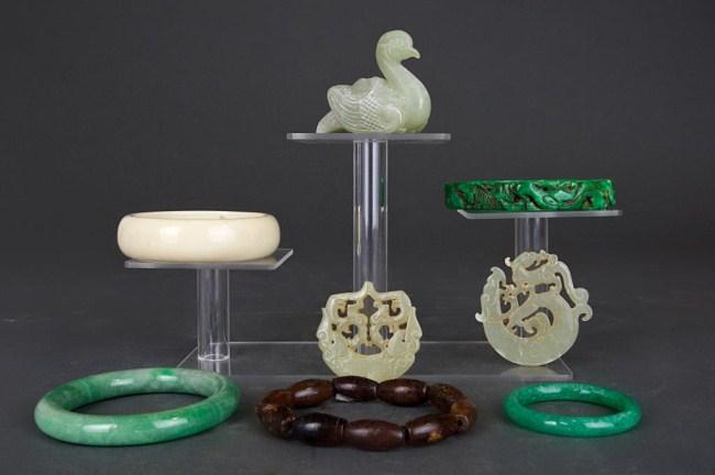 EIGHT ASSORTED CHINESE ITEMS: Comprising of three jade bangles, one carved jade figure of a swan, two white jade pendants, a carved bone bracelet, and a beaded bracelet. D: 3 1/4