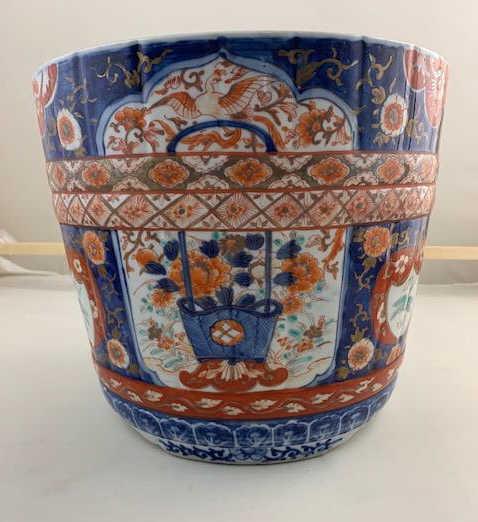 JAPANESE MEIJI PERIOD IMARI JARDINIERE: Beautifully hand-painted with panels of blossoming flowers around the body, against the royal blue background. H: 10 in. x W: 11 in.
