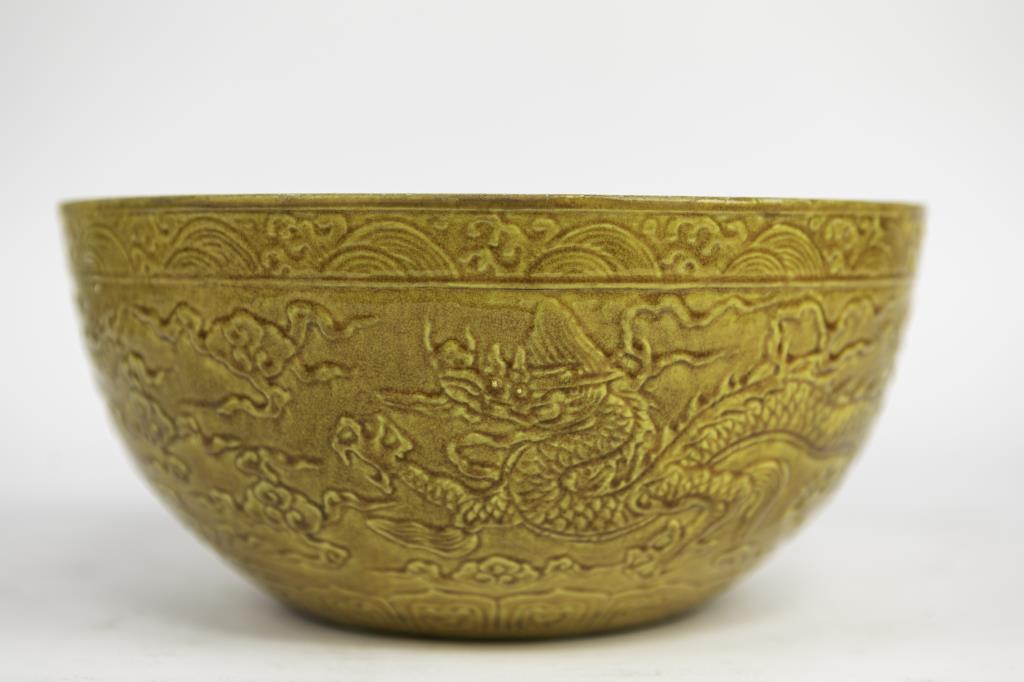 LARGE CHINESE YELLOW GLAZED BOWL: Decorated with two dragons in relief on the exterior. Double-ring six-character mark to read Xuande in the center. H: 5 in. Diameter: 11 in.