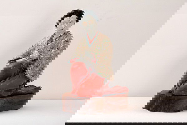 JAPANESE IMARI PORCELAIN FIGURE OF A LADY: JAPANESE IMARI PORCELAIN FIGURE OF A LADY, H:11 1/2", with raven long hair and wearing belted layed robe in genuflex position on wooden stand;