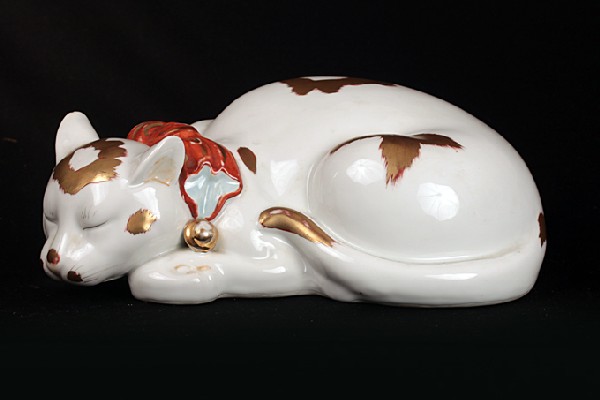 KUTANI PORCELAIN FIGURE OF A SLEEPING CAT: KUTANI PORCELAIN FIGURE OF A SLEEPING CAT, 19th century, H: 13 1/2", whimsically hand-painted with a red bow with bell and gold patches