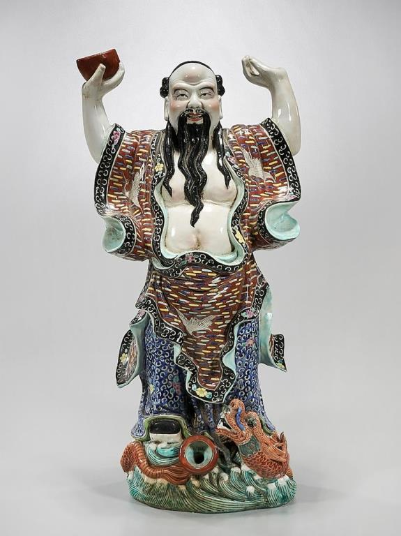 CHINESE PORCELAIN FIGURE OF AN IMMORTAL: Dressing in a flowing robe, standing atop of a dragon and raising his two arms. A raised mark on the bottom.H: 23 in.