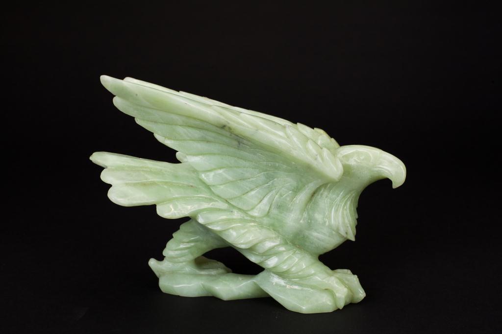 CARVED TOURMALINE EAGLE: Of a pale green tone, the bird is in a striding pose with its wings in takeoff position. H: 6 3/4 in.
