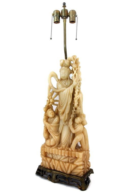 CHINESE SOAPSTONE CARVING OF A FEMALE DIETY: H: 34" holding flowers in stem with her attendants by the foot, on a rugged platform, lamp mounted at her back
