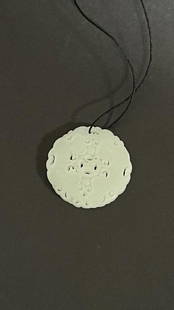 ROUND JADE PENDANT: Carved with intricate, elegant design.