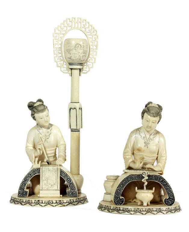 PAIR OF CHINESE IVORY OF WOMEN AT LEISURE: H: 10 1/2 in. (26cm), wearing similar robe in kneeling position and having identical work table and cylindrical base with ruyi head design; one lady holding a brush pegged on a scroll, and a lantern o