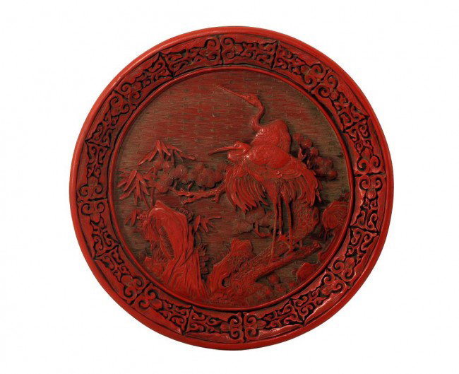 ANTIQUE CHINESE CINNABAR LACQUER PLATE: D: 11 3/4 in. (30cm), deeply carved centrally with cranes perched on pine trees against a carved diaper of fret scrolls, border with meandering tendrils