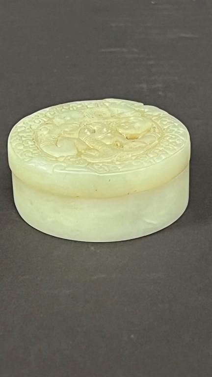 A ROUND CHINESE JADEITE TRINKET BOX: The cover carved and chased with a mermaid figure.