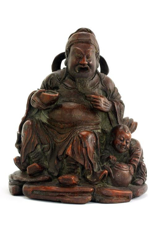 CHINESE CARVED WOODEN FIGURE OF TSAI SHEN YEH: H: 6 1/4 in. (16cm), the delightful carved figure sits on rockery, wearing loose robes and billowy scarf holding an ingot to his left hand and stoking his beard in the other, while a crouching attenda
