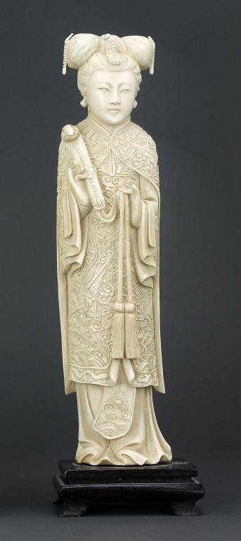 CHINESE CARVED IVORY OF AN EMPRESS: elaborately dressed, her hair held with a phoenix ornament, her right hand raises a tassled scepter. H: 10 1/2 in. (26.7cm)