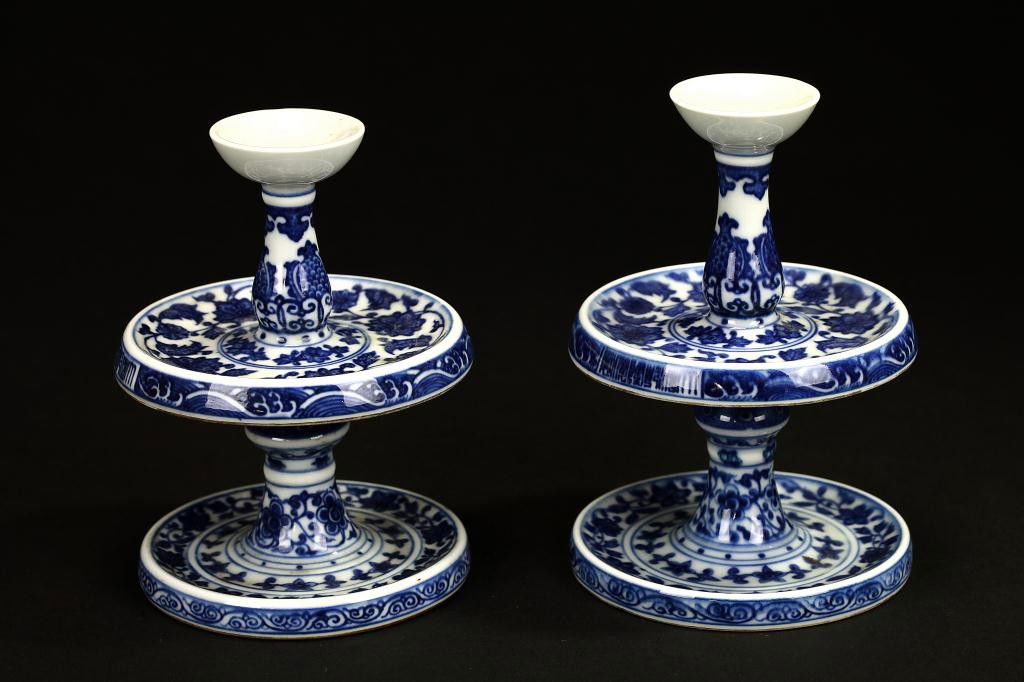 PAIR OF CHINESE BLUE AND WHITE CANDLE HOLDERS: each having a slender sectional form with a circular dish, all on a slightly smaller cylindrical base, hand-painted with meandering flowers and leaves. H: 4 3/4 in. (12cm)