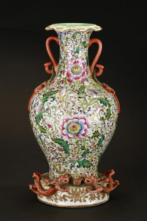 RARE CHINESE VASE WITH DRAGONS IN HIGH RELIEF: Carved in relief with flowers and foliage throughout, each of the two scepter handles support a swastika on tassel, raised on cylindrical base with gilded flowers and two applied moulded dragons chasi