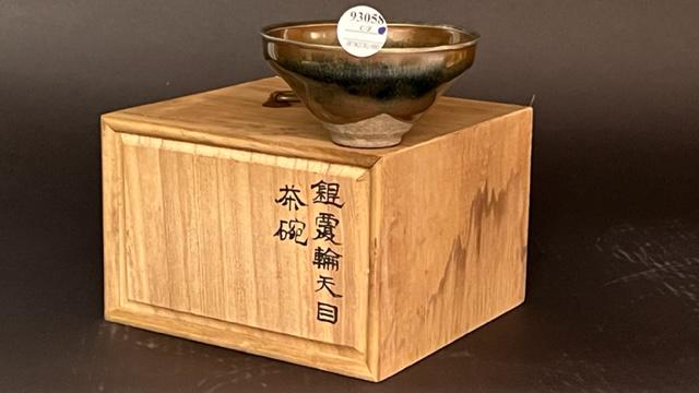 A GLAZED DEEP CONICAL JUNYAO STONEWARE BOWL: With splashes of graduated colors on its largely brown body, interior has mottled black splash resembling a mollusk shell pattern. With a wooden box. H: 2 1/2 in. D: 4 3/4 in.