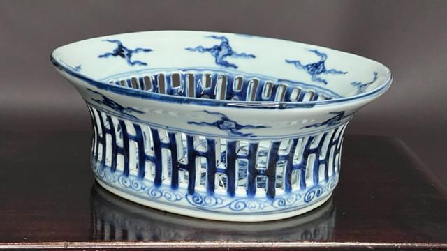 CHINESE BLUE AND WHITE OVAL PLANTER: Painted with clouds bordering the flared rim above an vertical openwork body. Base depicting of a large dragon within double rings. A six-character mark to read Xuande on the rim. H: 4 in. L: 11 in. W