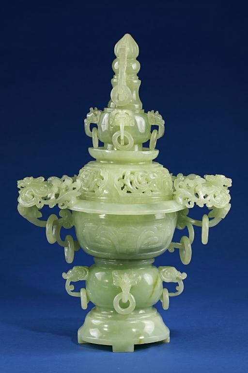 JADEITE CENSER WITH COVER: Composed of four sections on domed base; the lower globular jar decorated with four applied elephant head's masks with loose rings, supporting a deeply carved censer-like body flanked with winged chi