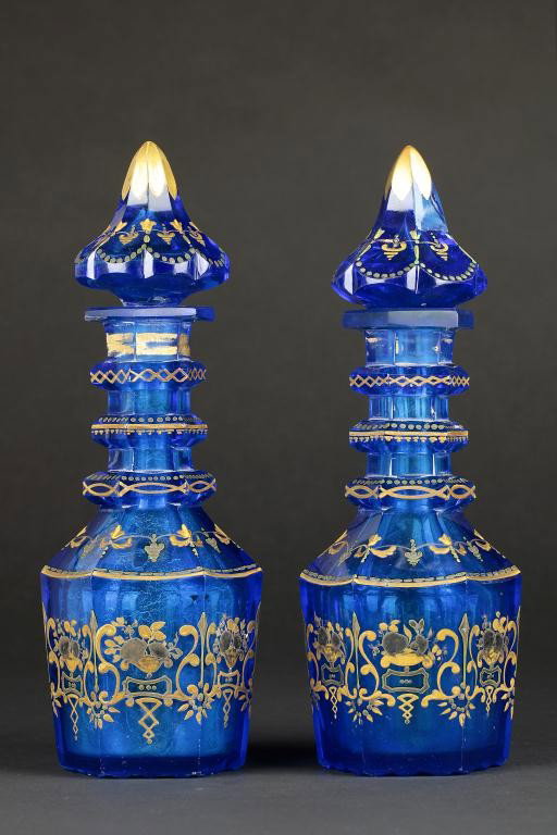 A PAIR OF HEAVILY GILDED TURQUOISE DECANTERS: Each bottle shape decanter has three three equally spaced flanges, with an acorn-form finial. H: 11 in. (28 cm)