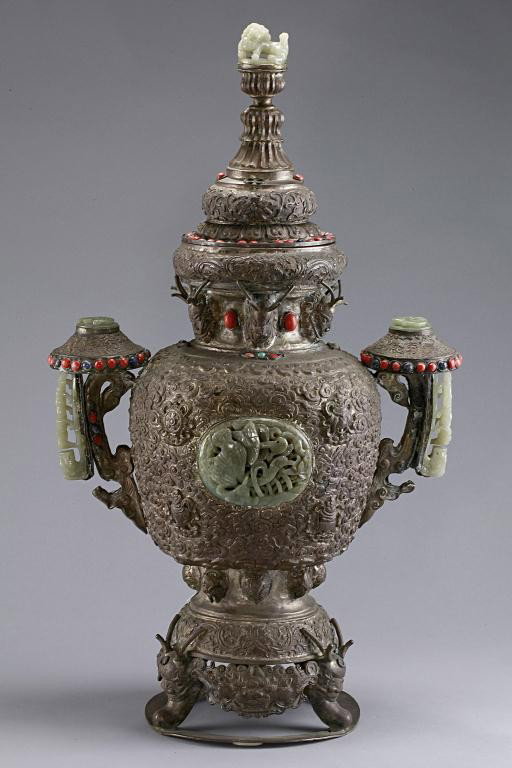 IMPRESSIVE BEJEWELED AND SILVERED MONGOLIAN TROPHY: Inlaid with jadeite on two roundels of the body, handles, and a foo dog as a finial.H: 23 1/4 in.(59cm)