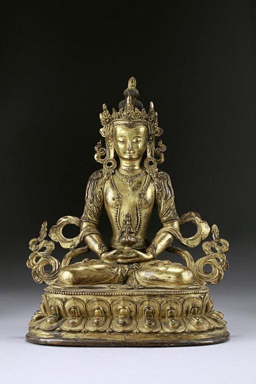 ANTIQUE TIBETAN GILT-BRONZE FIGURE OF A BODHISATTVA: Seated in vajraparyankasana, the hands clasped in front in dhyanasana holding the kalasha. Wearing a beautiful head piece with his scarf billowing on the sides of his arms. Seating on a double lotus p