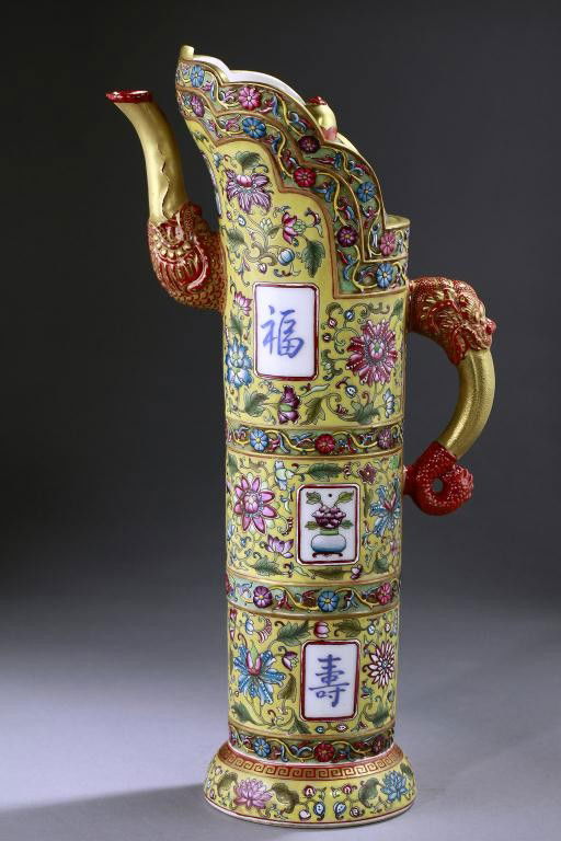 CHINESE TALL IMPERIAL YELLOW GROUND AND GILT EWER: Rising from a round base, the cylindrical body enameled and raised with flowers and bats within sectional panels, the spout and handle issuing from a beast's mouth. The domed cover surmounted with a l
