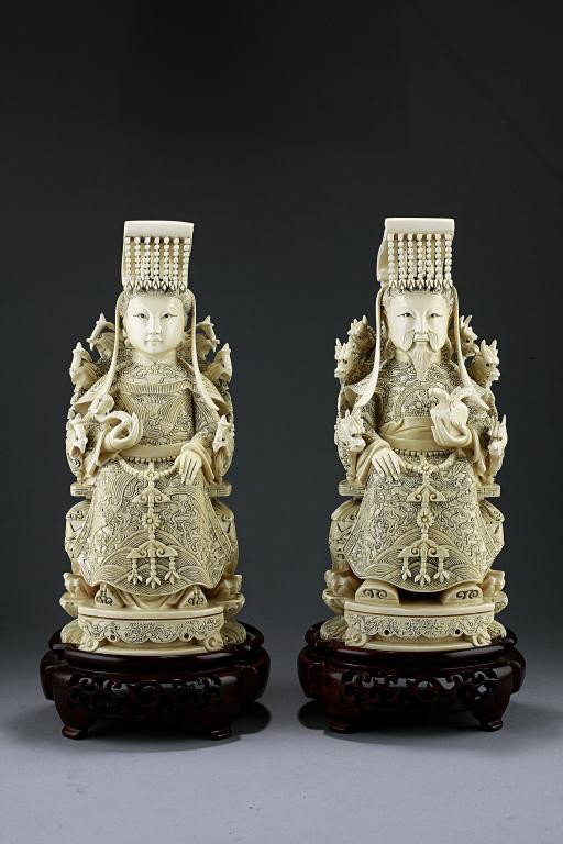PAIR OF CHINESE CARVED IVORY IMPERIAL FIGURES: Of a seated emperor and empress. The emperor wears court dress which intricately designed with a dragon in relief, sitting on a dragon chair, holding a bag in his left hand. The queen wears a court dr