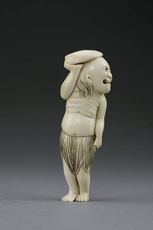 JAPANESE CARVED NETSUKE FIGURE OF A MAN: From the Private Collection of Harry Lawrence of Laguna Beach. Finely carved figure of a man turned to his side, shielding himself with a huge pod of leaf, and wearing a leaf skirt. H: 3 in.(7.5cm)