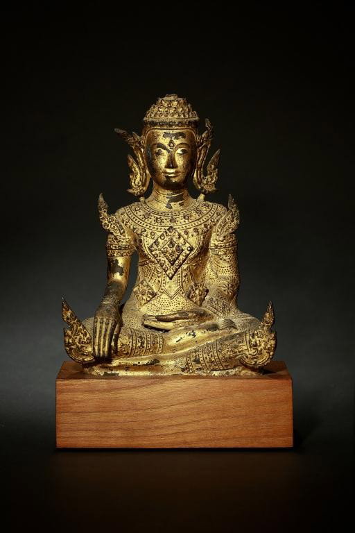 ANTIQUE THAI GILT BRONZE SEATED BUDDHA: Seated facing forward wearing a headdress and ornate robes; hand gesture with the right hand placed on the ground with all fingers touching, and the palm of the left hand faces inwards depicts the “