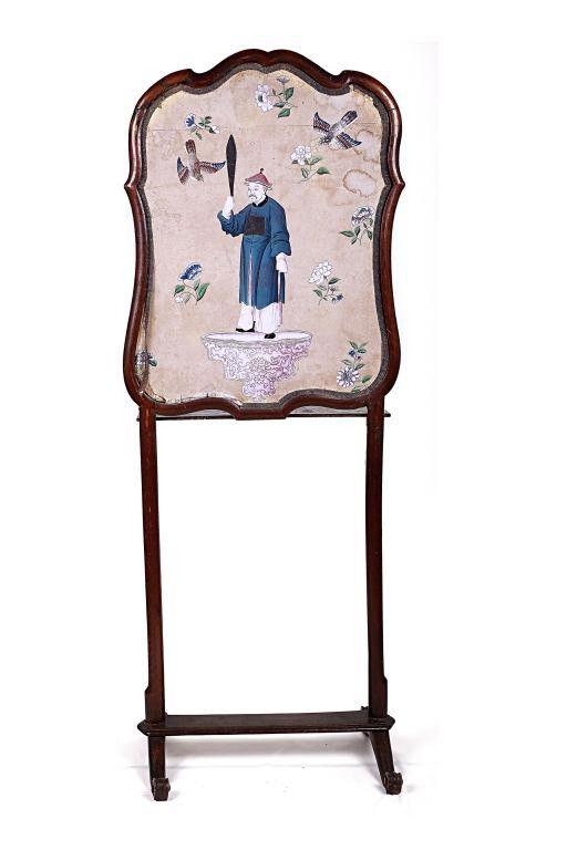CONTINENTAL ROCOCO WALNUT FIRE SCREEN: Two-sided cartouche wooden panel supported with tall slender legs on a stretcher above two scrolling bases; with one side decorated with a Chinese man holding out a sword on a rococo-mannered wall mou