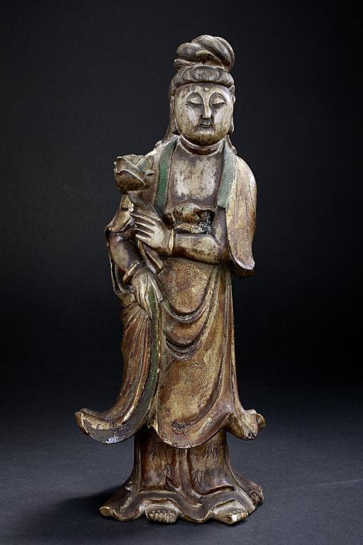 ANTIQUE CHINESE SOAPSTONE FIGURE OF A GUANYIN: Qing Dynasty. The Goddess of Compassion standing tall on bare feet, her face serene and eyes closed in deep contemplation, flanked by a pair of elongated earlobes, all beneath her finely incised hair 