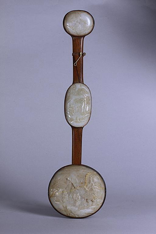 CHINESE NEPHRITE MOUNTED ON CARVED WOOD SCEPTER: A ruyi scepter with three carved inlays, a cartouche of figures in rockery setting doing various activities. L: 20 1/4 in.(51.5cm)