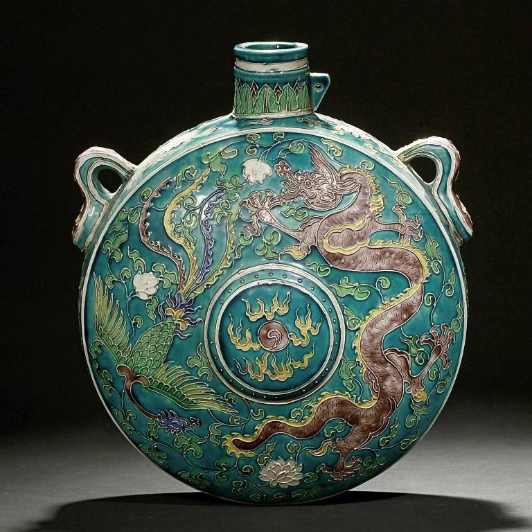 CHINESE TURQUOISE GROUND MOON FLASK: Decorated in copper red, and soft shaded tones with a five-clawed dragon leaping in pursuit of a phoenix amidst scrolling tendrils and floral blooms, half circling a flaming pearl in the center. Two e
