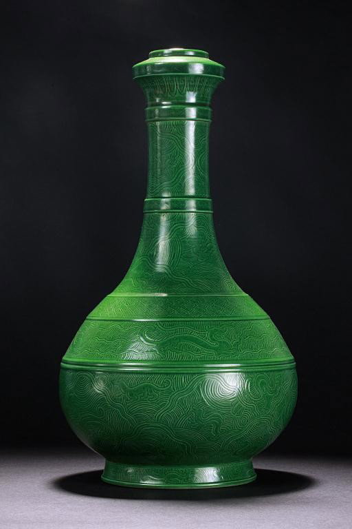 CHINESE MONOCHROMATIC GREEN BOTTLE VASE: Of globular form with a cylindrical neck and supported by a short flaring base; with etch designs of flying qilins amidst waving clouds around the neck and body separated by narrow flanges around the 