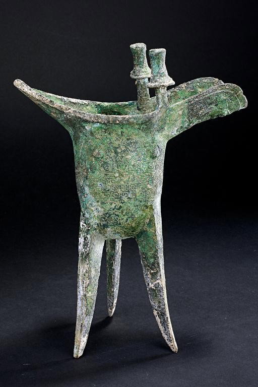 CHINESE WINE VESSEL, HAN DYNASTY PERIOD: Stable and graciously proportioned, the U-shaped body supported on three splayed blade feet, rising to a triangular protruding mouth rim peaking opposite the deep curving spout, flanked by two posts s