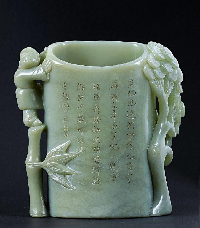CHINESE CARVED JADE BRUSH POT WITH CALLIGRAPHY: Exquisitely carved in high relief depicting a figure of a boy standing on a bamboo shoot, and a lush pine tree on the other side; with calligraphy on panels. H: 5 3/4 in.(14.5cm)