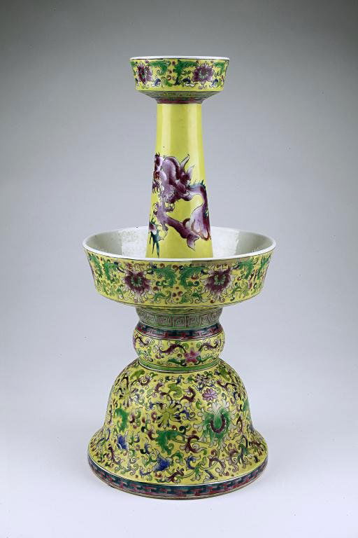 CHINESE FAMILLE JAUNE PORCELAIN CANDLESTICK: Formed in two sections, the hollow lower half of bell with lobed knop and slightly flared stem, and the upper half formed as a tapering neck with bowl-shaped mouth rising from a large circular dish, e