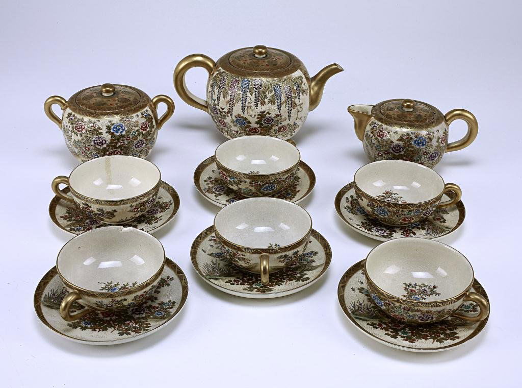 JAPANESE SATSUMA TEA SET: Composed of a teapot, sugar bowl, milk jug, and six sets of teacups and saucers; all enameled and designed with floral motif of peony and chrysanthemum flowers amidst leafy vines and tendrils; with se